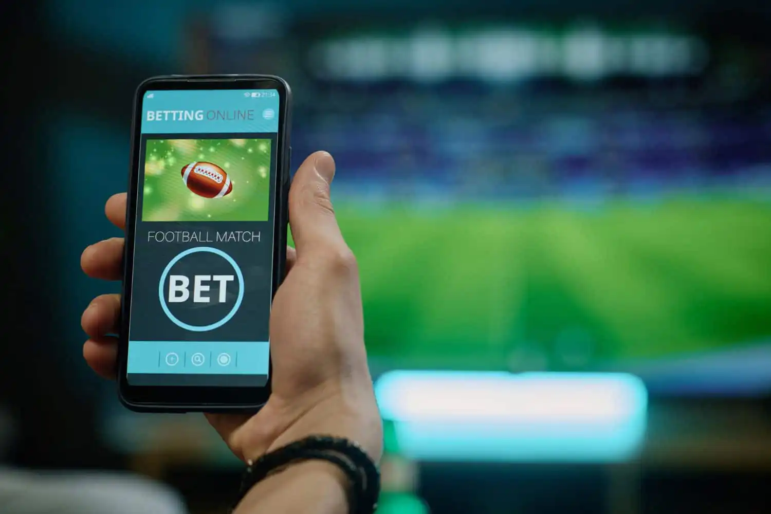 Hand holds a smartphone showing a betting app with a football match bet option on screen, titled Betting Online.